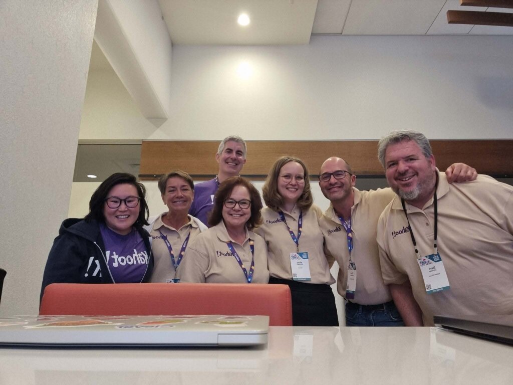 group of 7 people smiling at camera, wearing Kahoot! merchandise