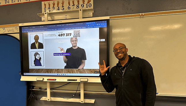 Picture of teacher in classroom with screen behind him